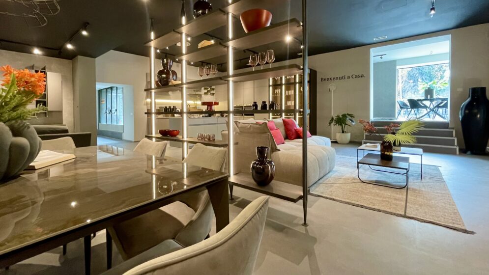 Showroom Anzalone Mobili a Roma: zona living con libreria illuminata e tavolo da pranzo